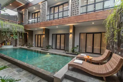 a swimming pool in front of a house with two chairs and a table at D Home Seminyak in Seminyak