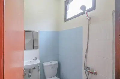 a bathroom with a toilet and a sink and a window at Catur Adi Putra in Denpasar