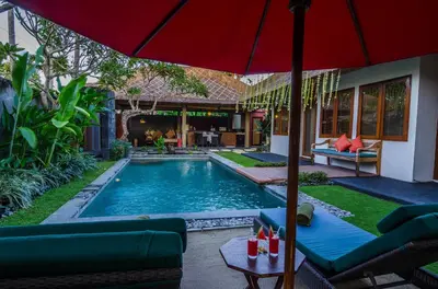 a backyard with a pool with a red umbrella at Imani Villas in Canggu