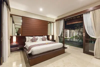 a bedroom with a large bed with a wooden headboard at Villa Litera Seminyak Bali in Seminyak