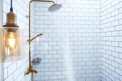 a bathroom with a shower with white tiled walls at Villa Brabhan Seminyak in Seminyak