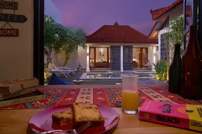 a table with a plate of cake and a glass of orange juice at Villa Brabhan Seminyak in Seminyak