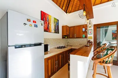 a kitchen with a white refrigerator and wooden cabinets at Awesome 1BR Villa in the heart of Seminyak in Seminyak