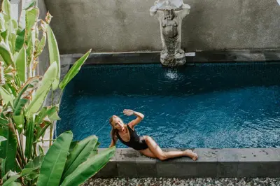 a woman sitting in a pool next to a fountain at Kuta Legian Villa 3 Bedroom Private pool in Legian