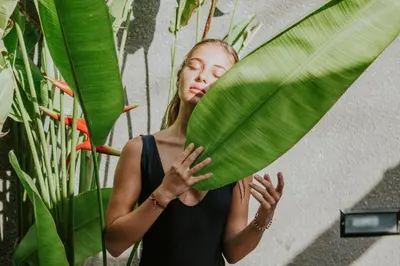 a woman is holding a large green leaf at Kuta Legian Villa 3 Bedroom Private pool in Legian
