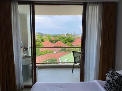 a bedroom with a bed and a glass door to a balcony at Stylish 2 Bedroom Penthouse Apt, Newly Refreshed, 50 Mbps, Pool, Gym, Resto in Kuta