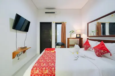 a bedroom with a bed with a tv on the wall at D'Tamblingan Guest House at Taman Griya Jimbaran RedPartner - Minimum Stay 30 Nights in Jimbaran