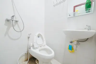 a white bathroom with a toilet and a sink at D'Tamblingan Guest House at Taman Griya Jimbaran RedPartner - Minimum Stay 30 Nights in Jimbaran
