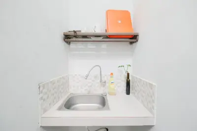 a kitchen sink with an orange laptop on a shelf at D'Tamblingan Guest House at Taman Griya Jimbaran RedPartner - Minimum Stay 30 Nights in Jimbaran