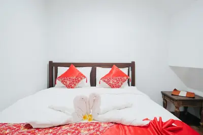 a bed with red and white pillows on it at D'Tamblingan Guest House at Taman Griya Jimbaran RedPartner - Minimum Stay 30 Nights in Jimbaran