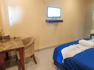 a room with a bed and a table and a television at Kuta Paradise 777 in Legian