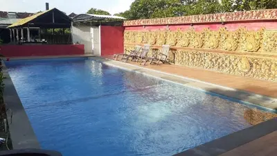 a swimming pool with blue water in front of a building at Kuta Paradise 777 in Legian