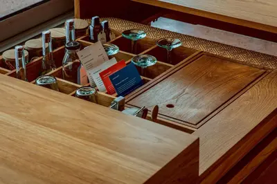 a wooden drawer with wine glasses and books at Desa Potato Head Bali in Seminyak