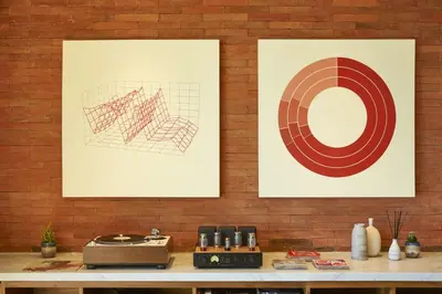 two framed pictures on a brick wall with a counter at Desa Potato Head Bali in Seminyak