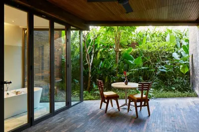 a patio with a table and chairs and a bath tub at Desa Potato Head Bali in Seminyak