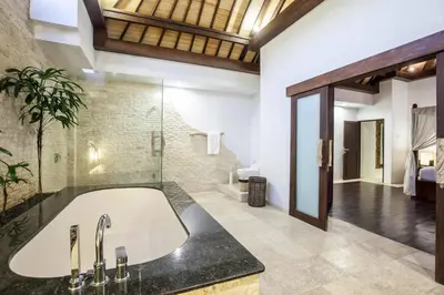 a bathroom with a large tub and a glass wall at Modern Private Villa Atala with Private XL Pool in Seminyak