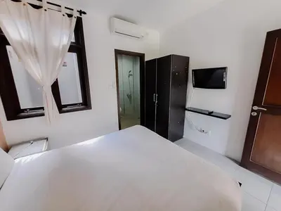 a bedroom with a large white bed and a tv at The Lavana Arimanu Kuta in Kuta
