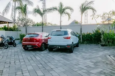 two cars parked in a parking lot with palm trees at The Lavana Arimanu Kuta in Kuta