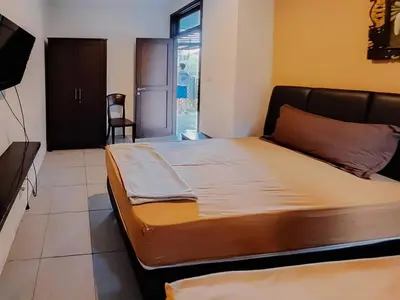 a bedroom with a bed and a tv and a chair at The Lavana Arimanu Kuta in Kuta