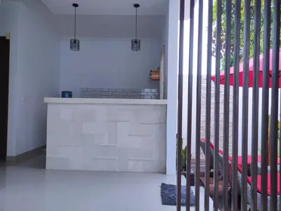 a kitchen with white walls and a staircase with red chairs at Pondok DenAyu Homestay in Kuta
