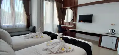 a hotel room with two swans on two beds at Pondok DenAyu Homestay in Kuta