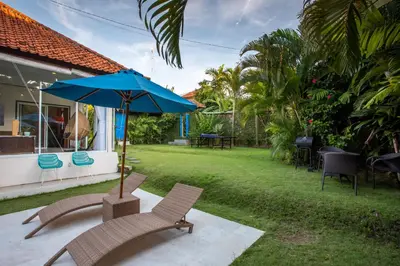 a patio with chairs and a blue umbrella at Villa Janitra in Seminyak