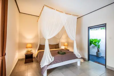 a bedroom with a bed with a mosquito net at Villa Janitra in Seminyak