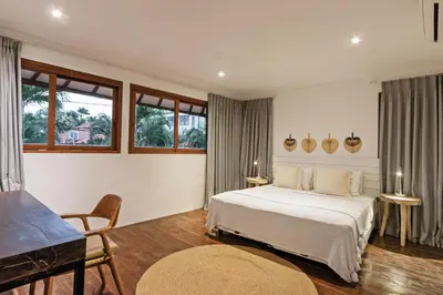 a bedroom with a bed and a table and some windows at Villa Senan in Seminyak