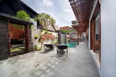 an outdoor patio with chairs and a swimming pool at Kusuma Living and Villa Seminyak in Seminyak