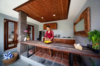 a woman sitting at a table in a kitchen at Kusuma Living and Villa Seminyak in Seminyak