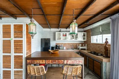 a kitchen with a wooden counter and chairs in it at Lolo #2 Apartment by Betterplace in Canggu
