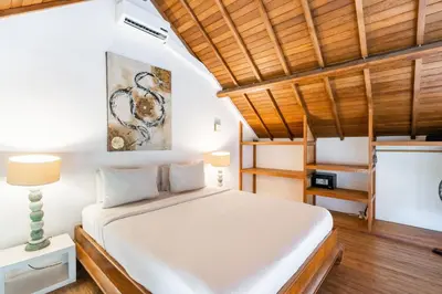 a bedroom with a white bed and wooden ceilings at Lolo #2 Apartment by Betterplace in Canggu