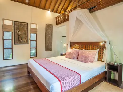 a bedroom with a bed with a canopy at Mango Tree Villas Jimbaran Bali in Jimbaran