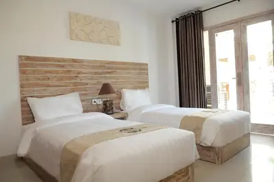a hotel room with two beds and a window at Tirtha Khayangan in Canggu