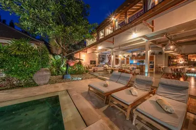 an outdoor patio with lounge chairs and a swimming pool at Villa Teman - Luxury 4BR Villa in Central Seminyak - HUGE POOL in Seminyak