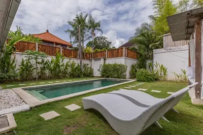 a backyard with a swimming pool and a hammock in the grass at Villa Alegria in Seminyak