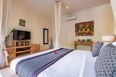 a bedroom with a bed and a flat screen tv at Central Seminyak Villa Martini in Seminyak