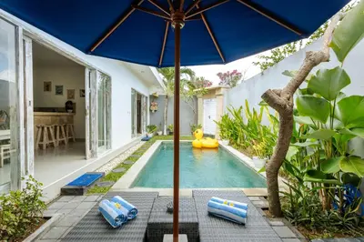 a pool with a blue umbrella next to a house at Villa Cathy, Seminyak - Private 3 Bedroom Pool Villa! in Seminyak