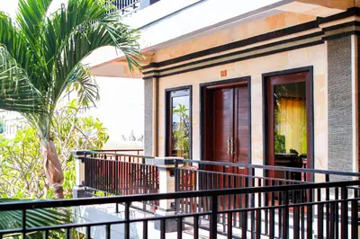 a house with a black railing on a balcony at Putu Guest House 2 in Canggu