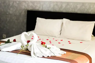 a bed with two towels and flowers on it at Putu Guest House 2 in Canggu