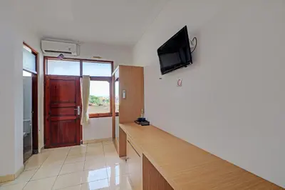 a room with a desk and a tv on the wall at Guest House Simalem in Legian