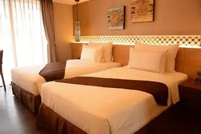 two beds in a hotel room with white sheets at Ramada by Wyndham Bali Sunset Road Kuta in Kuta