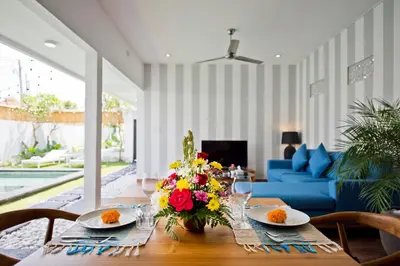 a dining room table with a vase of flowers on it at La Fortuna in Seminyak