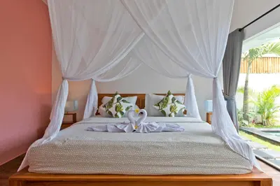 a bedroom with a bed with a white canopy at La Fortuna in Seminyak