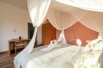 a bedroom with a canopy bed with white drapes at La Fortuna in Seminyak