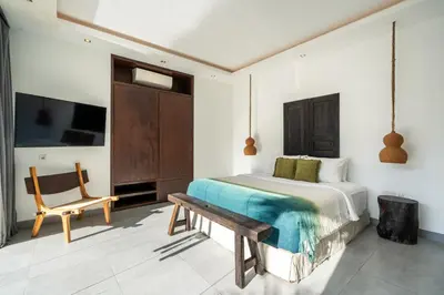 a bedroom with a bed and a bench and a tv at Villa WoW Canggu in Canggu