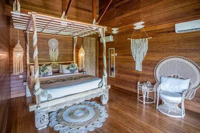 a bedroom with a bed and a chair at Atra Bambulogy Villa by Bambulogy Resort in Kerobokan