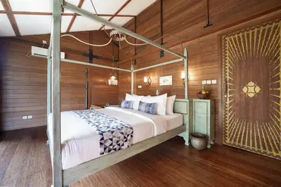 a bedroom with a bed in a room with wooden walls at Atra Bambulogy Villa by Bambulogy Resort in Kerobokan