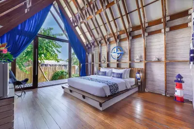 a bedroom with a bed and a large window at Atra Bambulogy Villa by Bambulogy Resort in Kerobokan