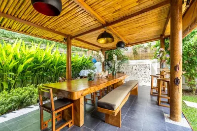 an outdoor dining room with a wooden table and benches at Madu Villa Seminyak in Seminyak
